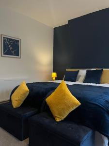 Un dormitorio con una cama azul con almohadas amarillas en NEW! 3 Bed House with Pool Table, Parking, Netflix en Nottingham