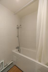 La salle de bains est pourvue d'une baignoire avec rideau de douche. dans l'établissement 32 m love nest studio with balcony, à Paris