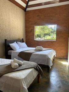 two beds in a room with a window at Pousada de Campo Estância Bahamas in Pirenópolis