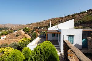 a white house with a hill in the background at House garden in Ioulis