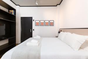 a white bedroom with a large bed with towels on it at BHomy Paulista Na Av Paulista com design BA608 in São Paulo