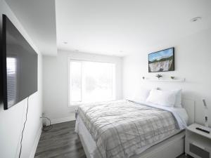 een witte slaapkamer met een bed en een televisie bij Executive 3 Bedroom Town House in Mississauga