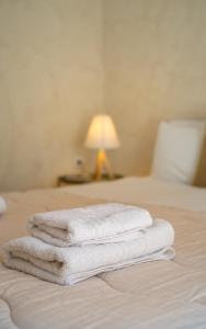 three white towels stacked on a bed with a lamp at Maisonette Pylos in Pylos