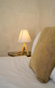 Maisonette Pylos في بيلوس: سرير مع طاولة عليها مصباح