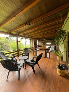 eine Holzterrasse mit Stühlen, einem Tisch und einem Tisch in der Unterkunft Casa Araucarias Refugio Natural en la Ciudad in Posadas