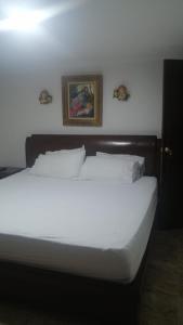 łóżko z białą pościelą i zdjęciem na ścianie w obiekcie habitacion amoblada con baño w mieście Bucaramanga