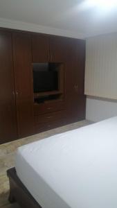 sypialnia z łóżkiem, telewizorem i drewnianymi szafkami w obiekcie habitacion amoblada con baño w mieście Bucaramanga