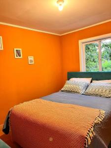 a bedroom with an orange wall with a bed at the house of flowers in Osorno