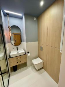 uma casa de banho com um WC, um lavatório e um espelho. em Blue Apartament - HOME APART em Ostróda