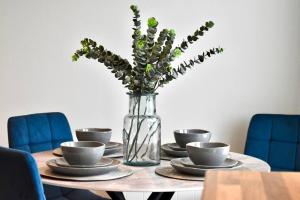 una mesa con platos y un jarrón con flores en *Penthouse Luxury Apartment 2min to City, en Carlisle