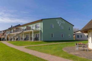 ein großes, grünes Gebäude mit einem Tisch und Stühlen in der Unterkunft Ferienanlage Süderhof in Breege