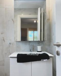 Liakada Guest House في أرتيميدا: حوض الحمام مع وجود منشفة سوداء على المنضدة