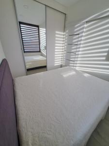 um quarto com uma cama branca e um espelho em Molino Apartamentai em Palanga