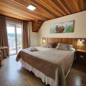 カンポス・ド・ジョルドンにあるPousada Kaliman Luxoの木製の天井のベッドルーム1室(大型ベッド1台付)