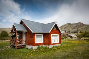 Patagonia Hostel في إل تشالتين: منزل خشبي صغير في حقل من الزهور