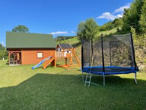 a playground with a slide and a house at Domki Za Górą in Jazowsko