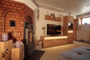 Una sala de estar con televisión y una pared de ladrillos. en FeWo Auer, en Bischofswiesen