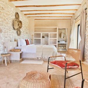 a bedroom with a white bed and a stone wall at Kaouki Lodge in Sidi Kaouki