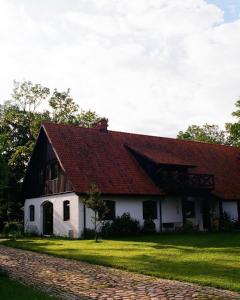 a white house with a red roof on a field at Poganty - Jałownik in Giżycko
