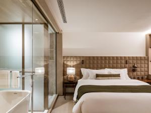 Pulso Hotel Faria Lima في ساو باولو: غرفة نوم بسرير كبير وحوض استحمام