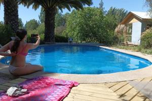 una mujer tomando una foto de una piscina en Posada Al Río, en Isla de Maipo