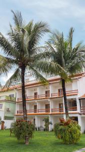 duas palmeiras em frente a um edifício em Casa Dela Pousada em Cabo Frio