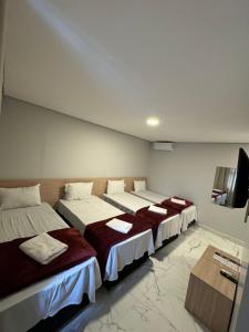 a room with three beds and a flat screen tv at Hotel Fênix Belenzinho in Sao Paulo