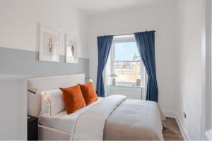 a bedroom with a white bed with blue curtains and a window at The Highlife Holborn in London