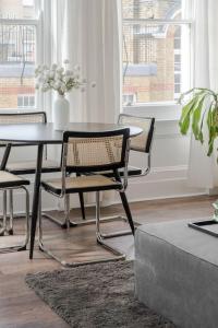 a dining room with a table with chairs and a vase of flowers at The Highlife Holborn in London