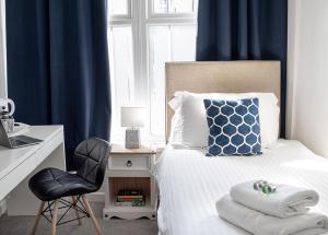 a bedroom with a bed with blue curtains and a chair at Royal Ashton Townhouse - Taunton in Taunton