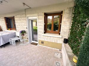 een huis met een patio met een tafel en een raam bij Appartement calme Antony, terrasse, vue jardin, proche Paris et Orly in Antony