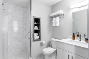 a white bathroom with a shower and a toilet and a sink at Classy Studio Downtown Near Hard Rock Casino in Cincinnati