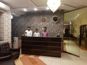 tres hombres parados detrás de un mostrador en un vestíbulo en Hotel Executive Lodges, en Bahawalpur