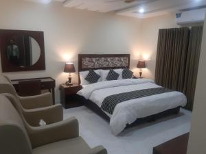 a bedroom with a bed and a mirror and a chair at Hotel Executive Lodges in Bahawalpur