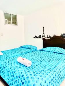 Un dormitorio con una cama azul con una toalla. en Apartamento amoblado para alquiler temporal zona Norte en Pasto