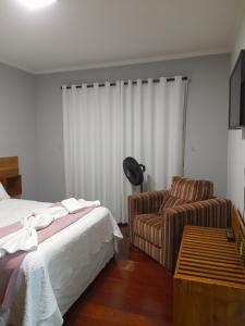 um quarto de hotel com uma cama e uma cadeira em Pousada Bem te vi em Bragança Paulista