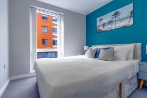 a bedroom with a large bed with blue walls and a window at Luxury 2BR Overlooking Portland Gardens in Bristol