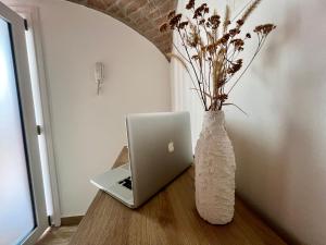 a vase with flowers and a laptop on a table at AIR σϝ HOME Aραɾƚɱҽɳƚ in Novi Ligure