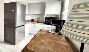 a kitchen with white cabinets and a stainless steel refrigerator at Apartamenty Marea Rentals Grunwaldzka Ustka in Ustka