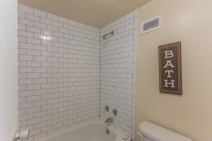 a bathroom with a tub and a white tiled wall at Affordable downtown Memphis apartment w views in Memphis