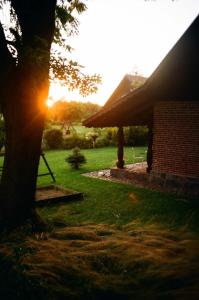 a house with the sun setting behind a tree at Poganty - Mały Domek in Giżycko