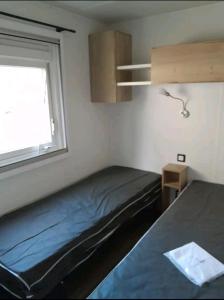 a small bedroom with a bed and a window at Mobil home in Piriac-sur-Mer