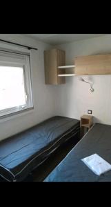Habitación pequeña con cama y ventana en Mobil home, en Piriac-sur-Mer