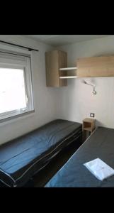 a small bedroom with a bed and a window at Mobil home in Piriac-sur-Mer