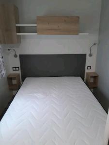 a large white bed in a room with two lights at Mobil home in Piriac-sur-Mer