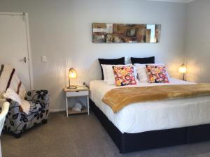 a bedroom with a bed with pillows and a chair at Secret Garden Guest Suite in Tauranga