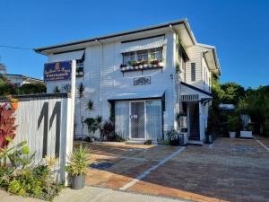 una casa blanca con un cartel delante en Hostel-Style GUESTHOUSE - for 18-40yrs en Caloundra