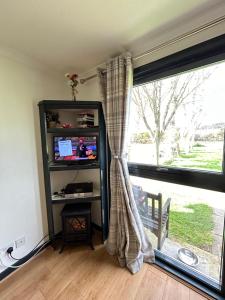 a living room with a tv and a window at Kilcoy Chalets in Muir of Ord