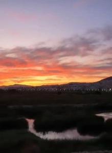 een zonsondergang boven een veld met een lichaam water bij La Perle de Tétouan in Tetouan