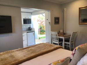 a bedroom with a bed and a kitchen with a table at Secret Garden Guest Suite in Tauranga
